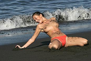 Lucy Clarkson topless in coral pants on a beach