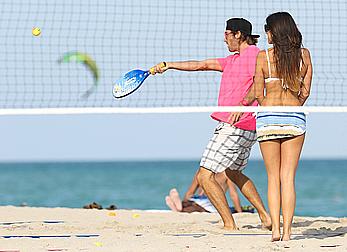 Claudia Romani on the beach in white bikini and jeans skirt