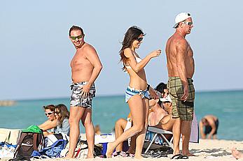 Claudia Romani on the beach in white bikini and jeans skirt