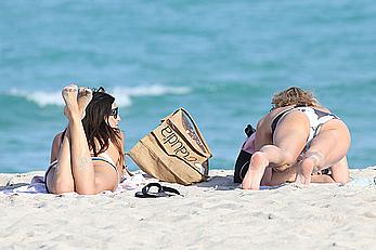 Claudia Romani on the beach in white bikini and jeans skirt