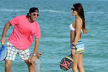 Claudia Romani on the beach in white bikini and jeans skirt