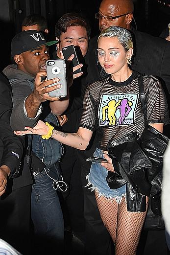 Miley Cyrus in a see through shirt and shorts