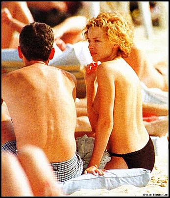 Kylie Minogue sunbathing topless on a beach